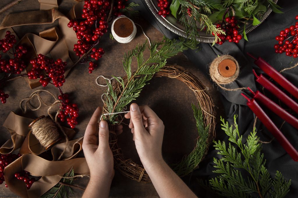 Hände beim Adventskranzbinden mit Material